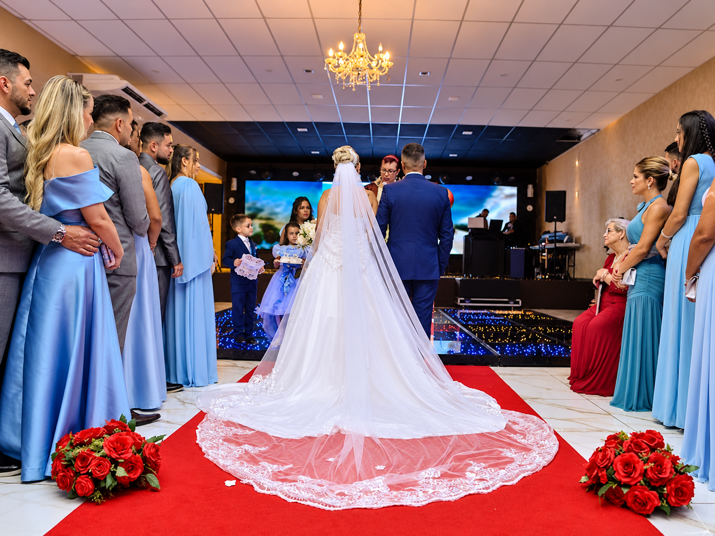 Cerimônia de casamento no salão, com convidados em pé ao redor da passarela
